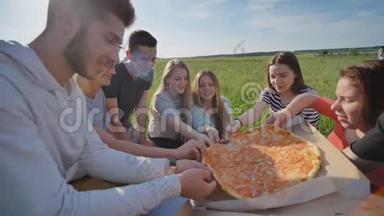 傍晚日落时分，孩子们的朋友们在户外挑选披萨。